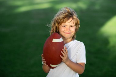 Sporcu çocuk. Amerikan futbolu. Parkta Amerikan futbolu topu tutan çocuk portresi.