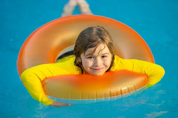 Kid playing with inflatable ring in swimming pool on hot summer day. Kid with inflatable ring in swimming pool. Summer vacation. Summer holiday. Summertime kids weekend