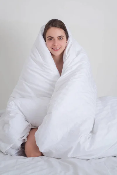 漂亮的年轻女人在家里的床上盖着温暖的毯子 快乐的女孩坐在床上 女孩早上在床上休息 女人早上在白色的床上醒来 — 图库照片