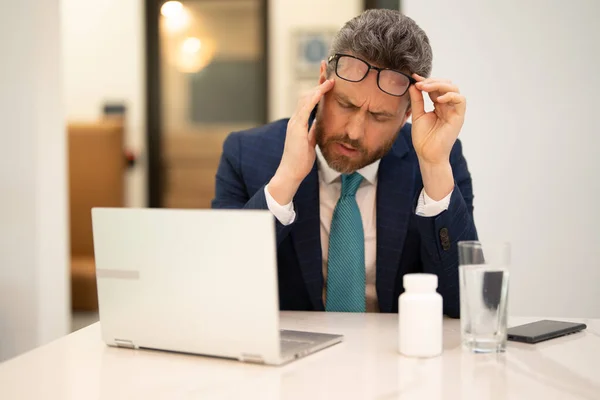 疲れた男は コンピュータの仕事の後に頭痛に苦しみ 目を閉じて頭に触れると疲れ 片頭痛を緩和する ビジネス上の問題 金融問題 危機の概念 — ストック写真