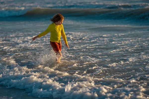 興奮した子供は夏の海で水を撒き散らして遊ぶ 夏休みだ 海で波の子供の遊び 海で遊んで水をこぼす小さな子供 子供は海でスプラッシュ水を再生します 夏休み — ストック写真