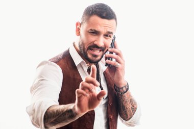 Telefondaki adam konuşuyor. Neşeli genç yakışıklı adam cep telefonuyla konuşuyor. Yakışıklı, heyecanlı, neşeli, sıradan giyinen adamın portresi. Telefon kullanılıyor