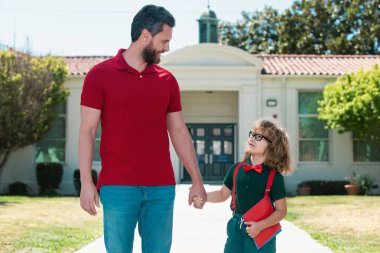 Baba oğlunu destekliyor ve motive ediyor. Çocuk ilkokula gidiyor.
