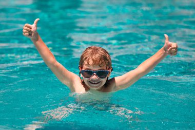 Yazın havuzda güneş gözlüklü heyecanlı bir çocuk. Havuzdaki çocuk.