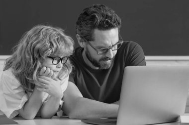 School teacher and child pupil learning at laptop computer, studying with online education e-learning in classroom. Teacher and little student portrait, teachers day