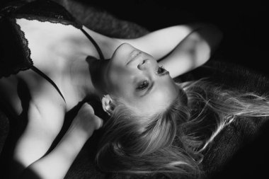 Gölgedeki kadın. Yüzünde gölgeler olan kadın model. Işıklı dramatik siyah stüdyoda baştan çıkarıcı ve şehvetli görünüyor. Sarışın kız yakın çekim yüzü