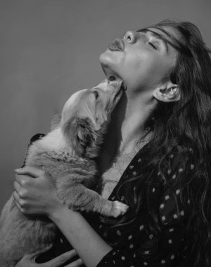 Yavru köpekli genç bir kadın, sarılıyor, sarılıyor, öpüyor, yalıyor. Hayvan dostu, hoş bir arkadaşlık.