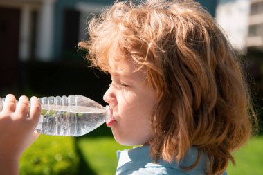 Şişeden su içen küçük şirin bir çocuğun portresi. Çocukluk ve ebeveynlik kavramı
