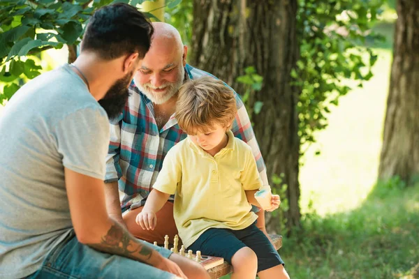 stock image Grandfather and grandson playing chess. Dad and Grandpa with his child son are playing Chess. Senior man workout in rehabilitation center. Generations men