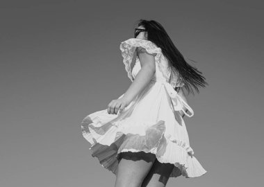 Gökyüzünde beyaz elbiseli hareketli kız. Moda elbisesi giymiş bir kadın model. Dışarıda kaygısız kadınlar