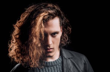 Ciddi yüzlü ve vahşi bir tarzı olan bir adam. Siyah arka planda gergin bir genç adam. Baştan çıkarıcı, kendine güvenen bir adam. Kameraya bakıyorum.