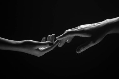 Parmaklarınla romantik dokunuş, aşkım. İki el birbirini gerer, siyah arka plan. Birbirine aşık çiftler, yaklaşın. Yardım eli, destek, arkadaşlık. Şefkat, şefkat dokunuşu