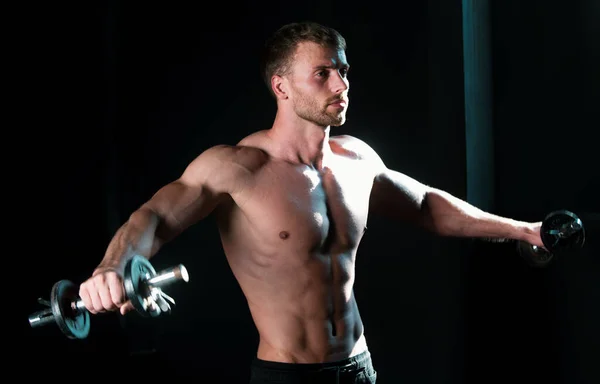 スポーティな胴 ダンベルの男 筋肉質の男がクロスフィットを行う スタジオで働いている若い男 運動中のアスリートマン — ストック写真