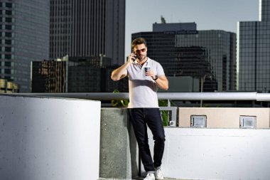 Şehir caddesinde telefonda konuşan yakışıklı bir adam. Büyük şehirde şehir hayatı yaşayan başarılı bir erkek model telefonda konuşuyor. Genç erkek manken dışarıda telefon kullanıyor. İş telefonu görüşmesi