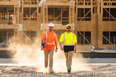 İnşaatçılar çalışıyor. İnşaat ekipmanlarıyla başarılı inşaat işçileri. Miğferli inşaat işçileri inşaat projesinde çalışıyor. İnşaat alanında kasklı iki işçi.