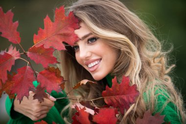 Sonbaharda güzel bir kız. Genç kadın sonbaharda sarı sonbahar yaprakları topluyor. Güzel kadın, sonbahar sarısı yaprağını tutar ve yüzüne düşer. Sonbahar döneminde şehvetli bir kadının portresi.