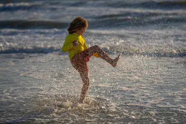 晴れた夏の日には波の海の近くの湿った海岸で走っている屈託のない少年を追放した 夏のビーチで走っている子供 気をつけて 夏の海を走る興奮した子供 かわいい子供は夏の海で走る — ストック写真