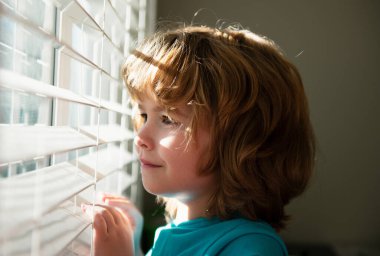 Karantina konsepti. Koru kendini. Evde tek başına kal. COVID-19 tecrit. Pencereden bakan çocuk. Koronavirüs salgını
