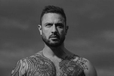 Seksi bir adamın baştan çıkarıcı yüzü. Maço kendinden emin görünüyor. Gökyüzünde ciddi profili olan bir adamın yakın portresi.