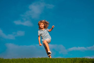 Mutlu çocuk dışarıda eğleniyor. Çocuk yaz parkında oynuyor. Küçük çocuk yeşil çimlerde koşuyor. Doğayla oynayan çocuklar