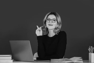 Tahtadaki oldukça genç bir lise ya da üniversite öğretmeni. Genç beyaz kadın öğretmen portresi. Tahta arka planda parmağıyla işaret ediyor.