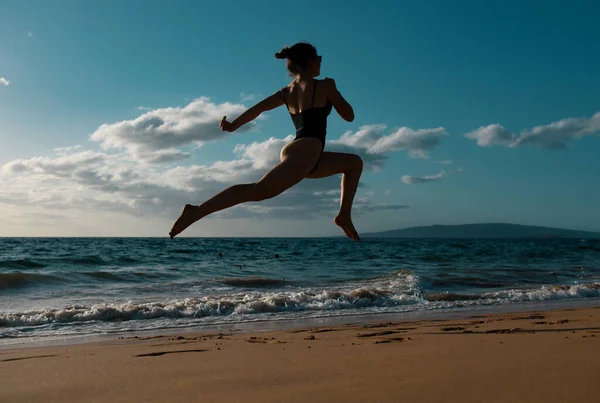 女は海岸を走る ウォータープールで海の波に沿って走るアクティブなスポーティーな女の子は フィット感と健康を維持します 女性のフィットネス ジョギングワークアウト 夏休みのスポーツ活動 — ストック写真