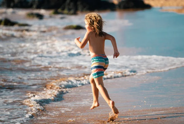 子供たちは海のビーチ沿いの海岸に近い水を介して実行している 少年は海岸沿いを走る 夏休みの残りの子供たち — ストック写真