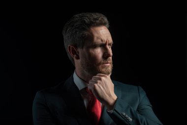 Siyah arka planda duran izole iş adamının portresi. Olgun iş adamı düşünür, yakından bakar.