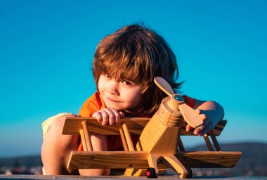 Komik çocuk ya da çocuk pilot oyuncak uçakla oynuyor, başlangıç özgürlüğü ve tasasız. Uçma hayalleri. Çocuk gökyüzüne karşı oyuncak uçakla oynuyor. Tatlı çocuk suratı.