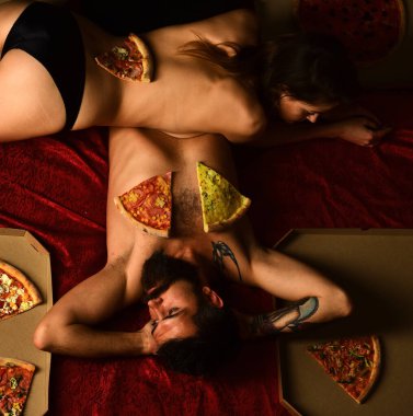 Sevgiyle pizza. Şehvetli çift yatakta pizza yemekten hoşlanır. Sakallı adam ve seksi kadın eve pizza sipariş etti. Hızlı ve kolay pizza dağıtım servisi. Evde yatakta pizza yiyen seksi çift.
