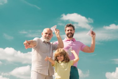 Three different generations ages grandfather father and child son playing with toy plane outdoors. Family adventure, imagination, innovation and inspiration clipart