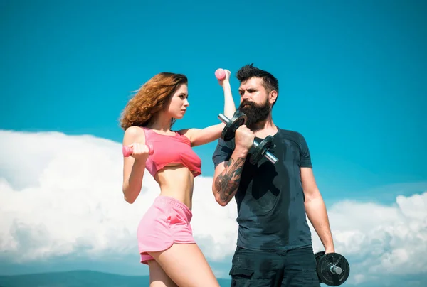 stock image Fit couple doing exercising outdoors with dumbbell. Sportive woman and man, team. Sport, dumbbell and fitness, couple sports. Sporty sexy couple showing workout wiht dumbbells. Sports fitness girl