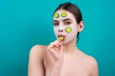 Yüz bakımı. Temiz ciltli güzel bir genç kadın. Yüzünde salatalık dilimleri ve yüz maskesi olan genç ve güzel bir kadın. Cilt bakımı ve tedavi. Yüzünde salatalık maskesi