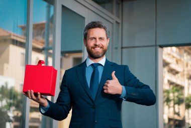 Harika bir hediye. Elinde hediye kutusu olan ve şehrin karşısında dururken gülümseyen adam
