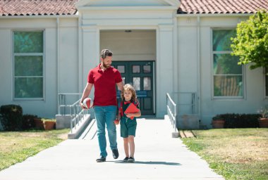 İlkokulun ebeveyni ve öğrencisiyim. Öğretmen ve okul parkının yanındaki sırt çantalı tatlı okul çocuğu.