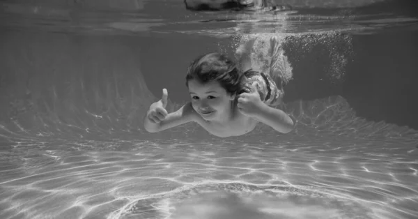 水中の子供は水泳プールで泳ぐ 夏のアクティビティや健康的な子供のライフスタイル 熱帯のリゾートで子供たちと夏休み 子供の男の子と親指を水中で — ストック写真