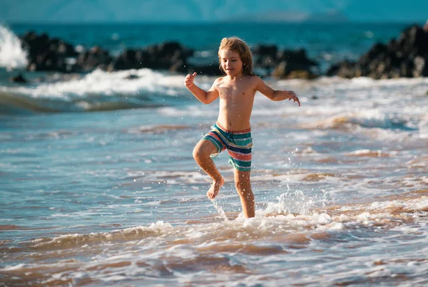 休暇中の夏の日に海の波の中で活発な小さな男の子が飛び散っています 子供と家族の休日の概念 — ストック写真