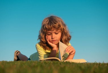 Akıllı çocuk parkta kitap okuyor.