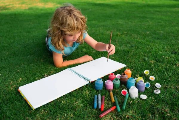 子供たちは創造的な休暇を描きます 子供は自然を背景に楽しい草の中に横たわって公園で描く — ストック写真