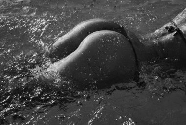 Bikini girl with perfect body in water. Female wet buttock with drops. Natural butt, fit sporty cropped body. Summer holiday with sexy bikini model