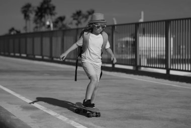 Yaz parkında kaykay yapan bir çocuk. Küçük çocuk kaykay yapmayı öğreniyor. Çocuklar için açık hava sporu. Çocuklar kaykay yapıyor. Çocuk kaykaya biniyor. Hadi gidelim. Kaykay yapan çocuk.