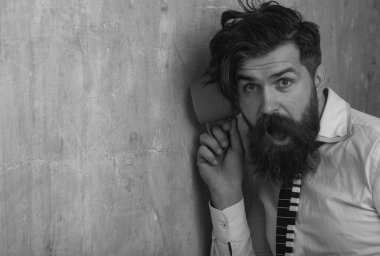 Elinde kupayla duvardan dinleyen bir adam. Sırlar ve dedikodu konsepti. Komşu ve sır. Sakallı komik adam fincanla dedikodu duyar. Duvarı dinleyin. Taranmamış dağınık saçlı sakallı adam.