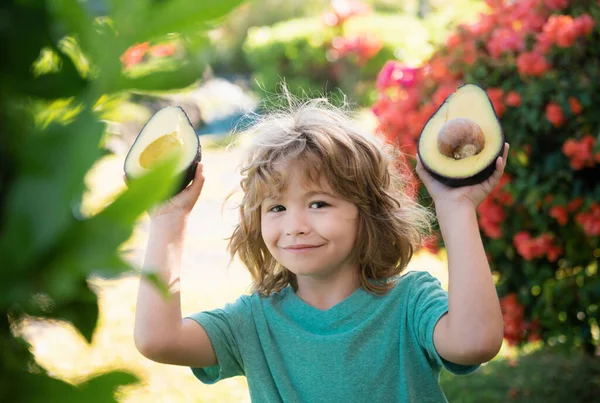 自然を背景にアボカドを食べて楽しむ子供 子供のための健康食品コンセプト — ストック写真
