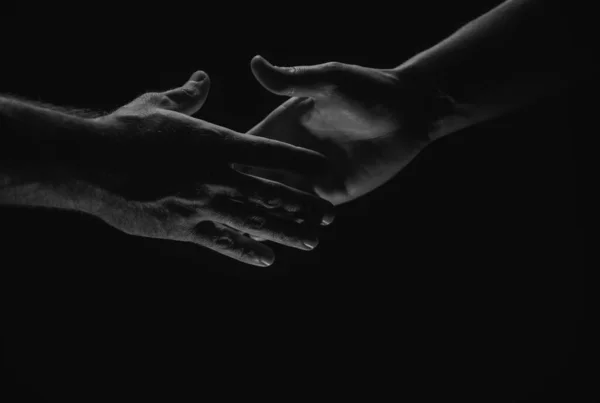 Handshake. Men holding hands isolated on black. Connection and human relations. Male hands rescue. Friendly handshake, friends greeting, friendship. Rescue, helping gesture or hands. Helping hand