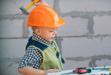 İnşaatta tadilat için aletleri olan küçük miğferli bir mimarın portresi. İnşaatçı çocuk, marangoz çocuk ve inşaatçı aletleri var. Çocuk tamircisi ve tamircisi.