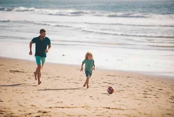 父と息子はビーチでサッカーやサッカーをします 夏の日に遊んでいる子供の男の子とパパ — ストック写真