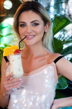 Moda mankeni şık bir yaz elbisesi içinde kokteyl partisinin tadını çıkarıyor ve lezzetli bir alkol kokteyli hazırlıyor. Yazın kokteyl içen ve tatilin tadını çıkaran seksi kadın.