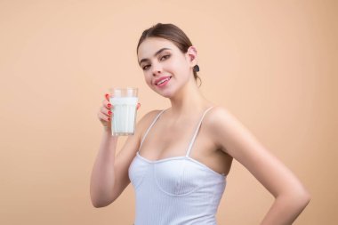 Süt içen bir kız, stüdyo arka planında izole edilmiş. Genç kadın saf taze sütün tadını çıkarıyor. Susamış kadının elinde cam süt var. Sağlıklı süt.