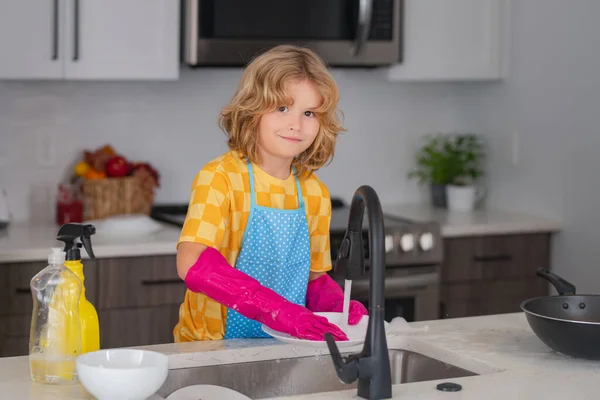 子供の掃除食器キッチンシンクスポンジ食器洗い機 台所での子供の掃除の肖像画 子供の家政婦は石鹸水で皿を洗う かわいい面白い男の子キッチンで皿を洗う — ストック写真