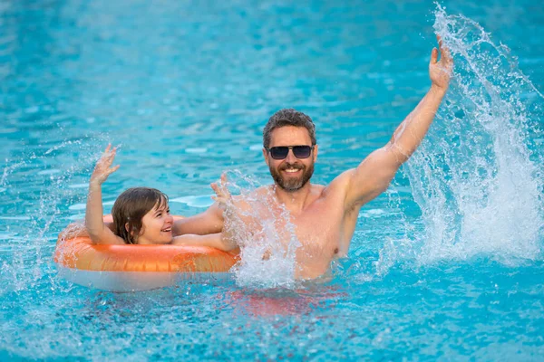 父と息子はプールで楽しんでいます プールの水に子供をはねお父さん 父と息子が一緒にプールで遊んでいます 夏のスイミングプールでお父さんと子供の水泳 夏休み — ストック写真